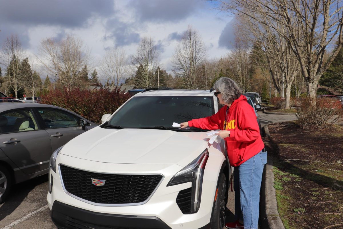 Olympia High School staff Tamara Liska placing a warning for a future ticket on a student’s vehicle.